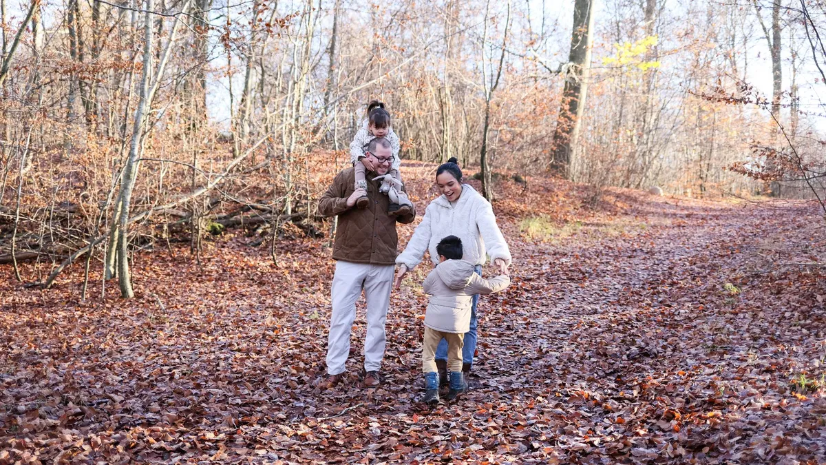 Família passejant per un camí de bosc en una excursió de natura amb nens